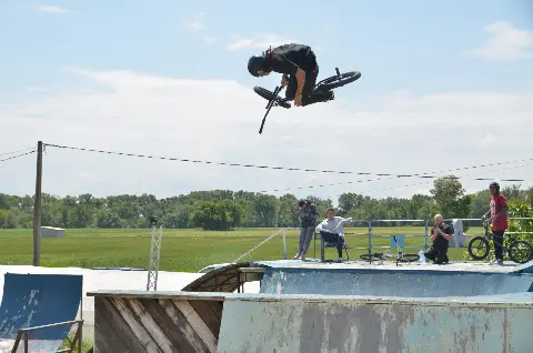 Rider en BMX en saut au-dessus d'une rampe, spectateurs et photographe sur la plateforme