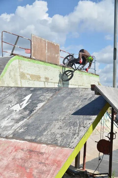 Rider au casque vert en BMX sur le rebord d'une rampe usée vert et gris