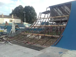 Ossature métallique courbe d'une grande rampe en construction, à côté d'une rampe bleue