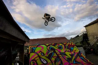 Rider en BMX en plein saut, haut dans le ciel, au-dessus d'un module couvert de graffitis colorés