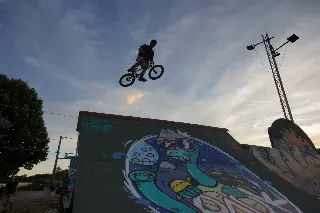 Rider en BMX en saut au-dessus d'un module peint d'un personnage coloré, vu en contre-plongée