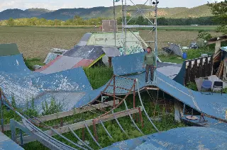 Homme debout sur des rampes bleues usées au milieu des herbes, champs et collines en arrière-plan