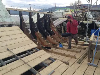 Personne en sweat rouge sur le chantier d'une rampe en bois aux gabarits courbes