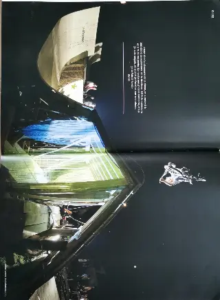 Double page de magazine avec une photo de nuit d'un rider en BMX en saut devant une grande courbe éclairée