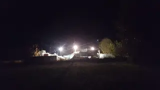 Park éclairé par des projecteurs dans la nuit, vu de loin