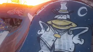 Personnage à chapeau haut-de-forme peint sur une rampe bleue, dans la lumière rasante du soleil