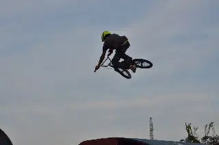 Rider au casque jaune en saut, à contre-jour sur un ciel gris