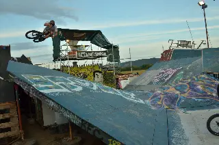 Rider en BMX en saut au-dessus d'une courbe sous l'enseigne « Tetanos Park », rampes graffées au premier plan