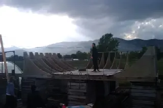 Personne debout sur une rampe en construction aux gabarits de bois, sous un ciel d'orage