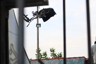 Rider en BMX à l'envers en plein saut, vu à travers des barreaux, spectateur derrière une rampe